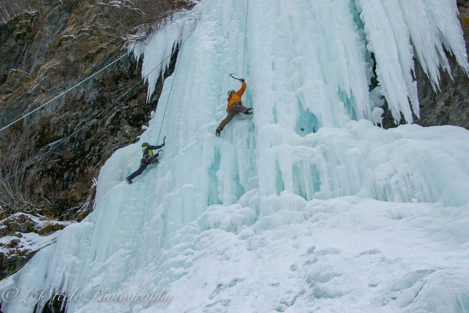 Two people ice climbing a frozen waterfall.
